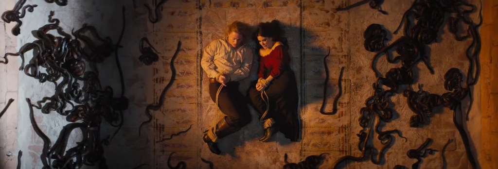 Sandra and Channing tied up surrounded by snakes.