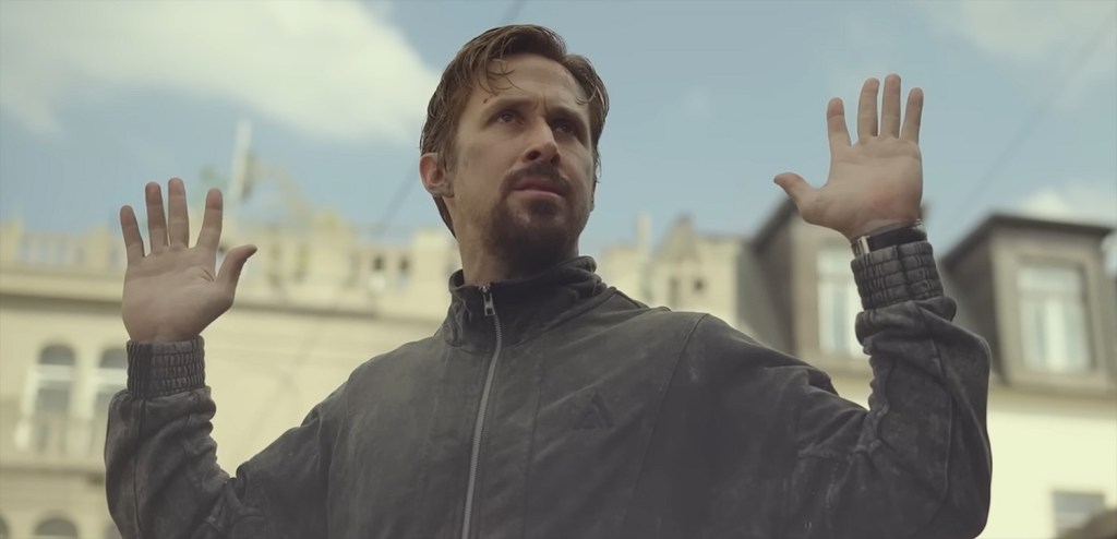 Ryan Gosling with his hands up.