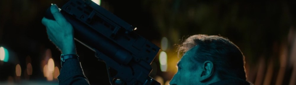 Liam Neeson fires a grenade launcher.