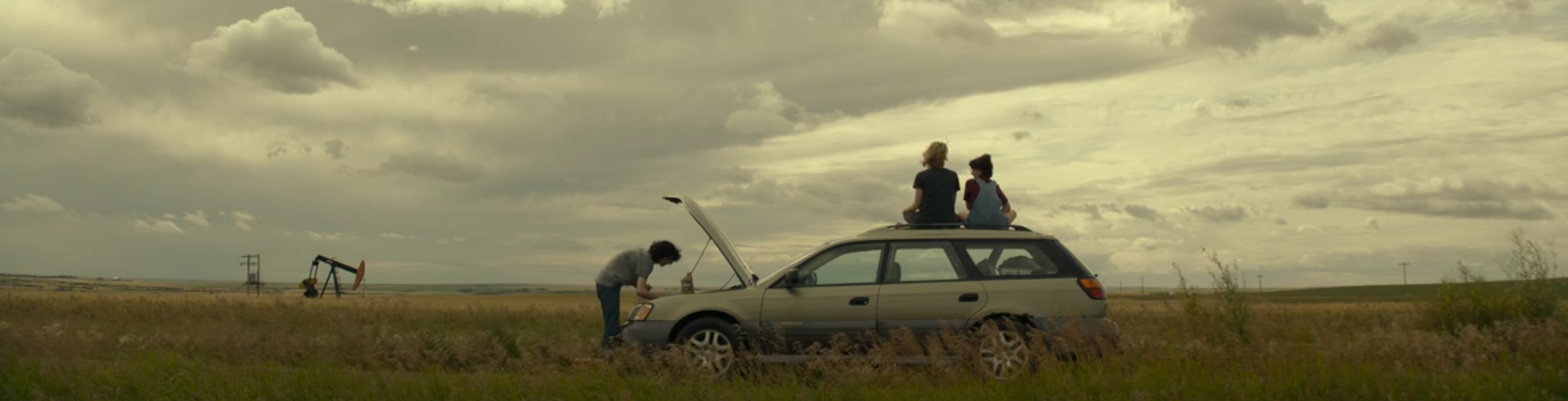 The family sit on a broken car.