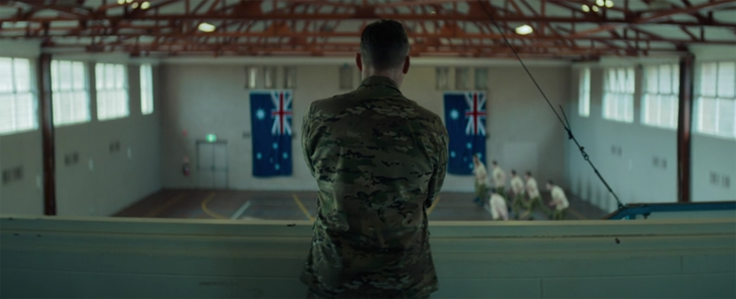 Sam Worthington stands between two flags.