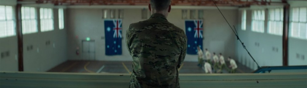 Sam Worthington stands between two flags.
