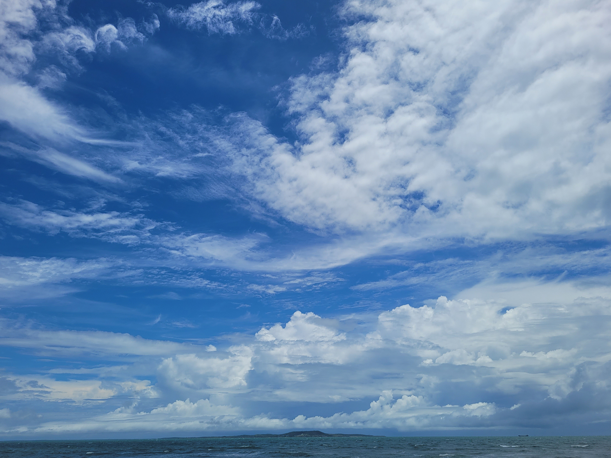 A cargo ship hangs in the distance like a toy on the water.