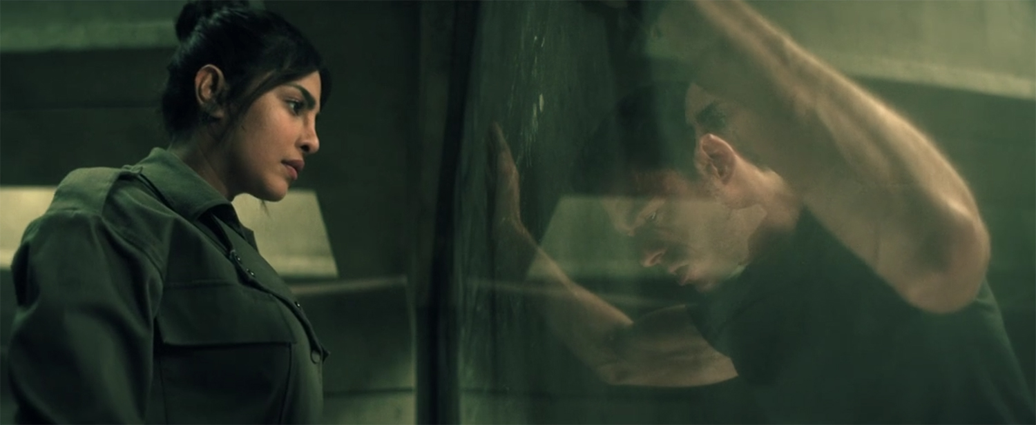 Nadia looks at Mason through a two-way mirror.