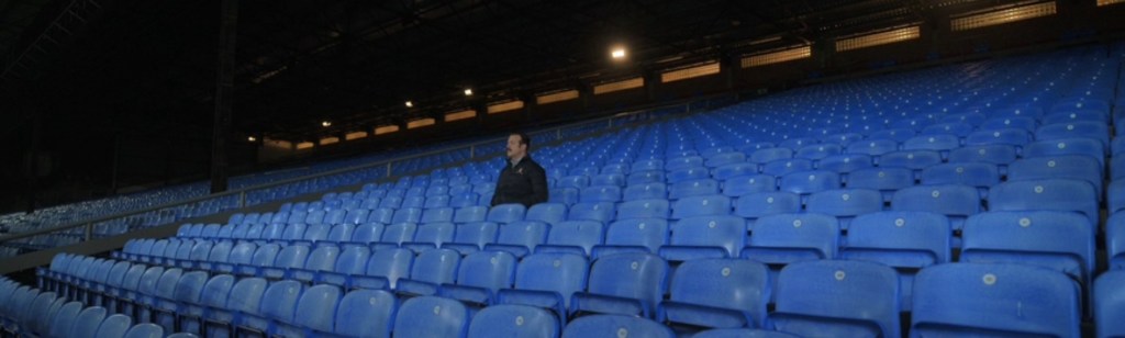 Ted sits alone in the stands