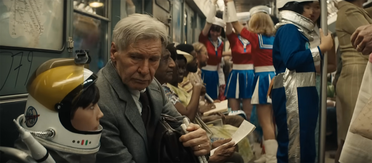 Indy on a train as everyone is dressed up in space outfits.