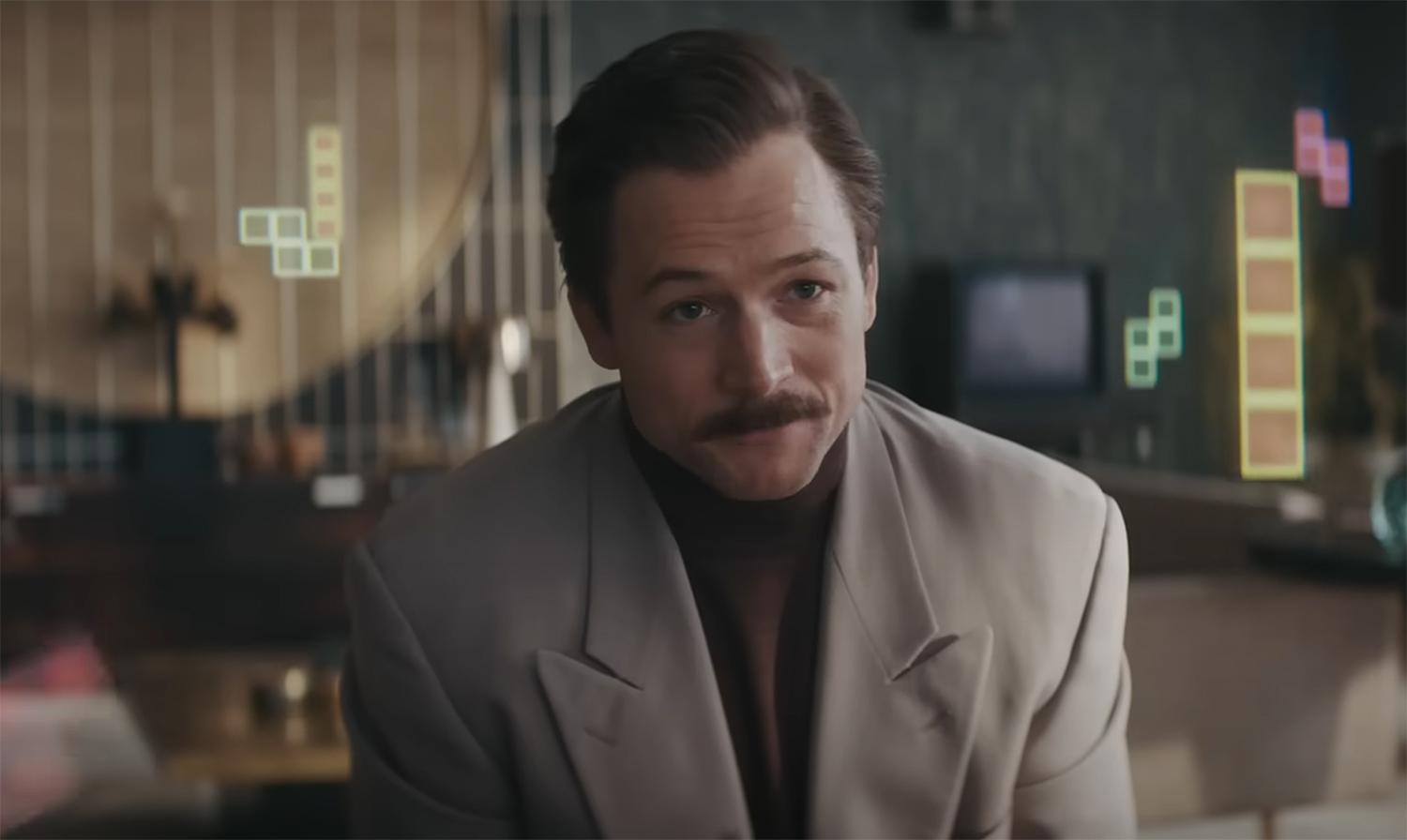 Taron Egerton as Tetris pieces fall down behind him.