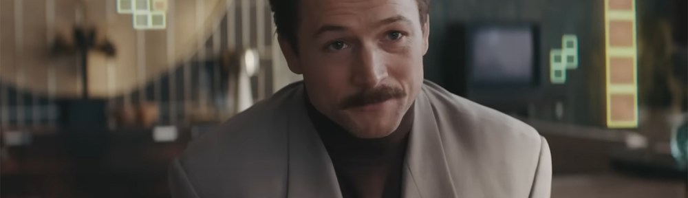 Taron Egerton as Tetris pieces fall down behind him.