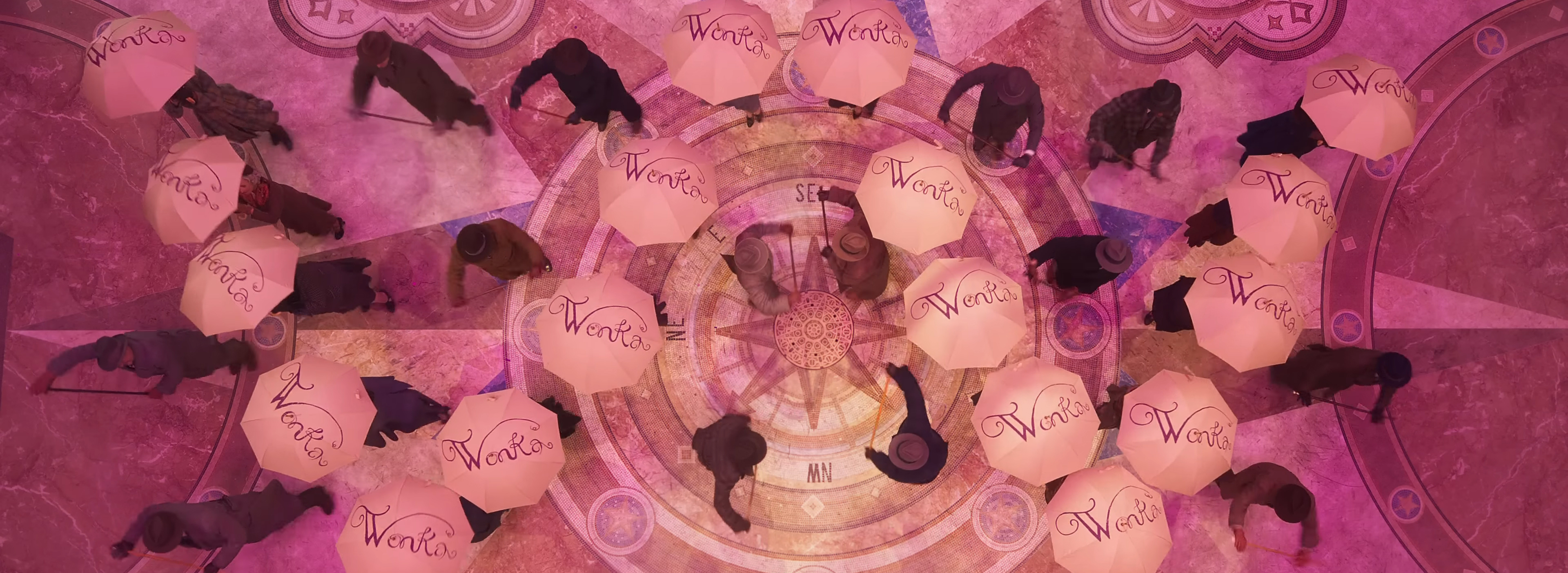 An overhead shot of dancers making a W out of umbrellas.