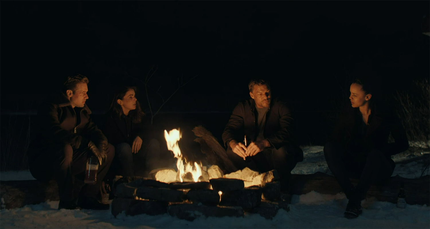 The gang sit reminiscing around a fire.