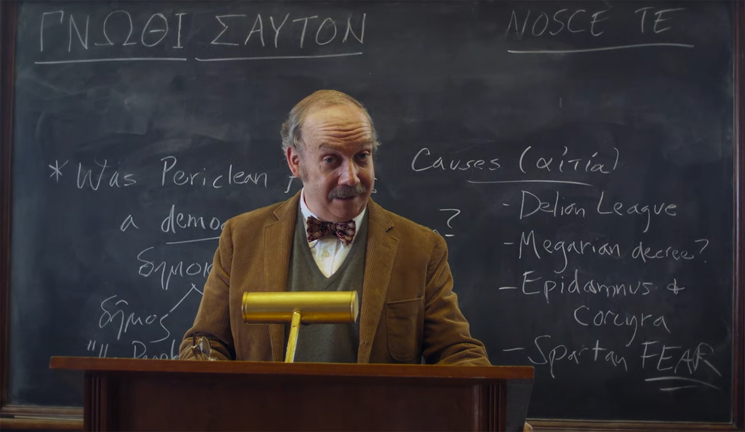 Paul teaching Greek History behind a blackboard.