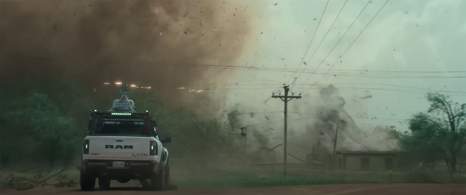 A truck backs away from a tornado.