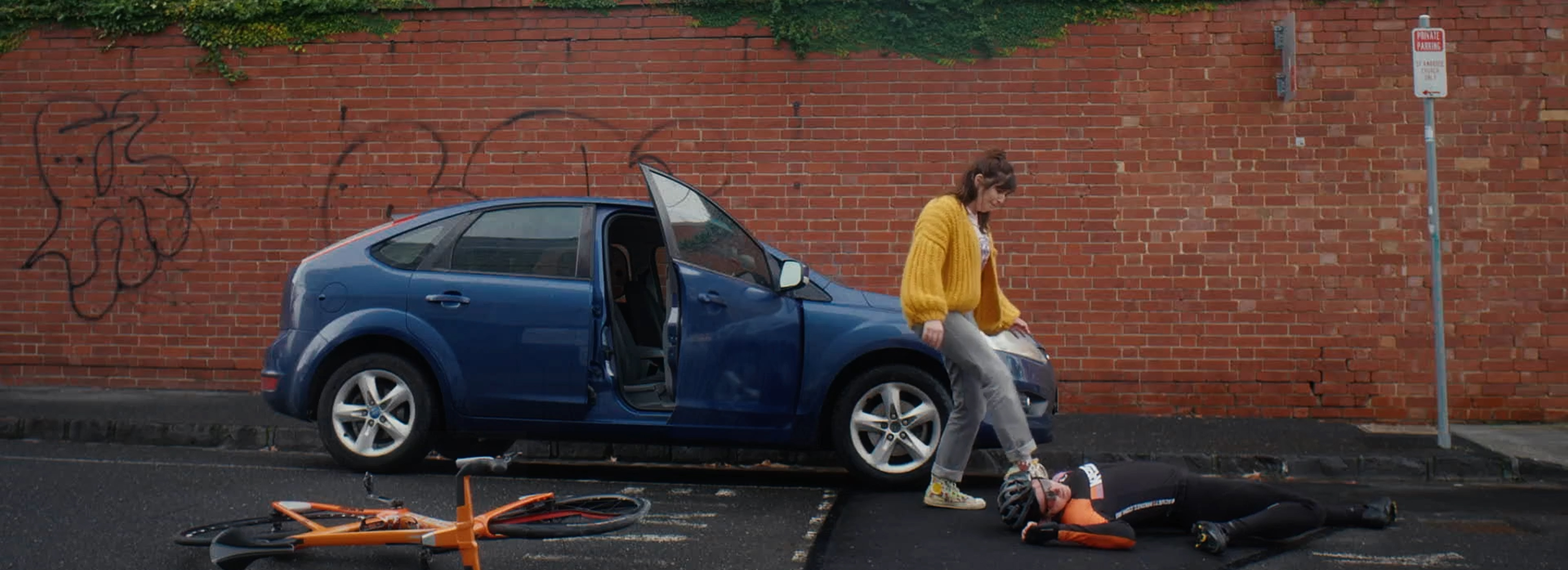 Abi kicks the cyclist she just hit with her car.