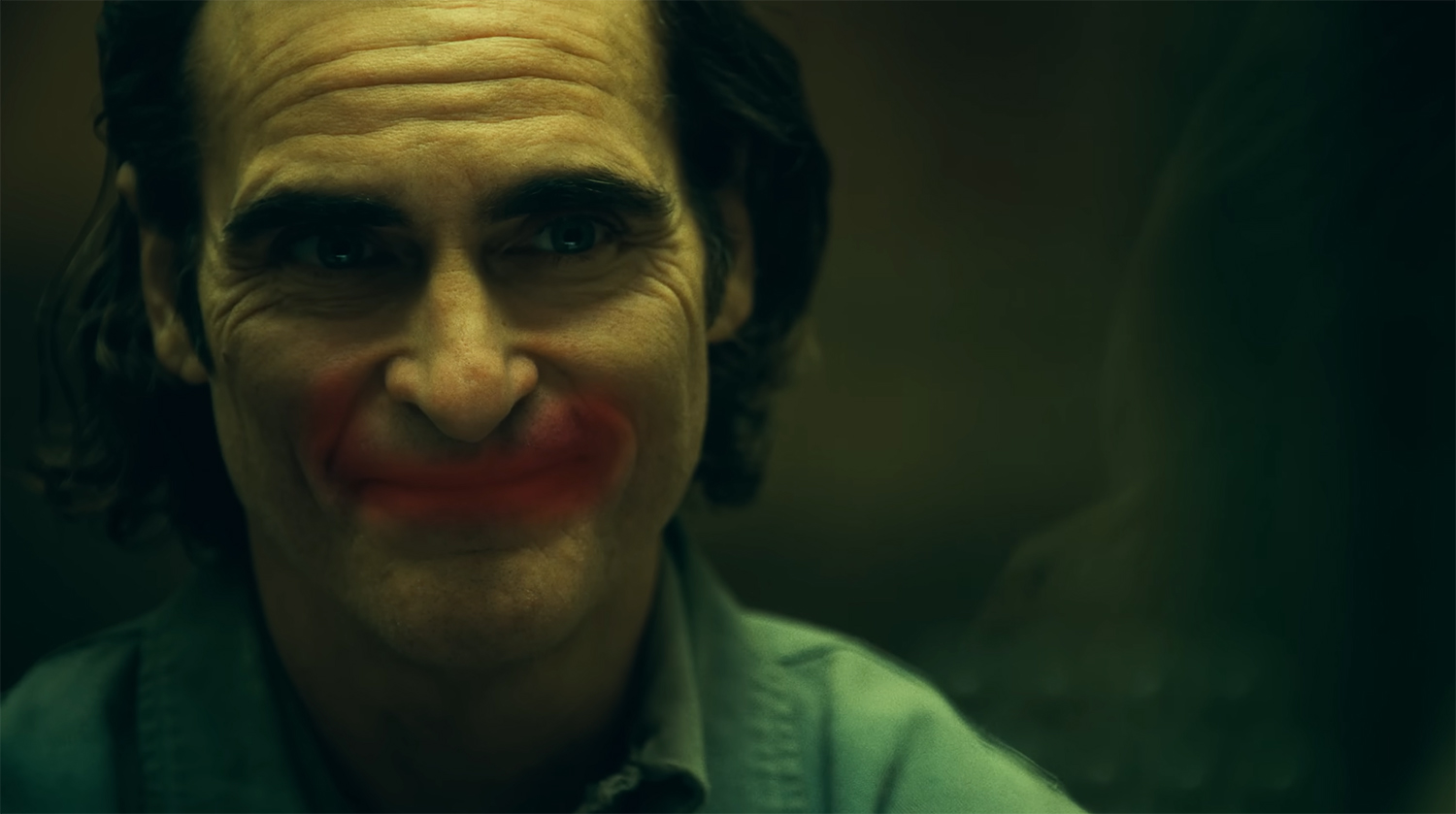 The Joker smiles with red paint on the glass.