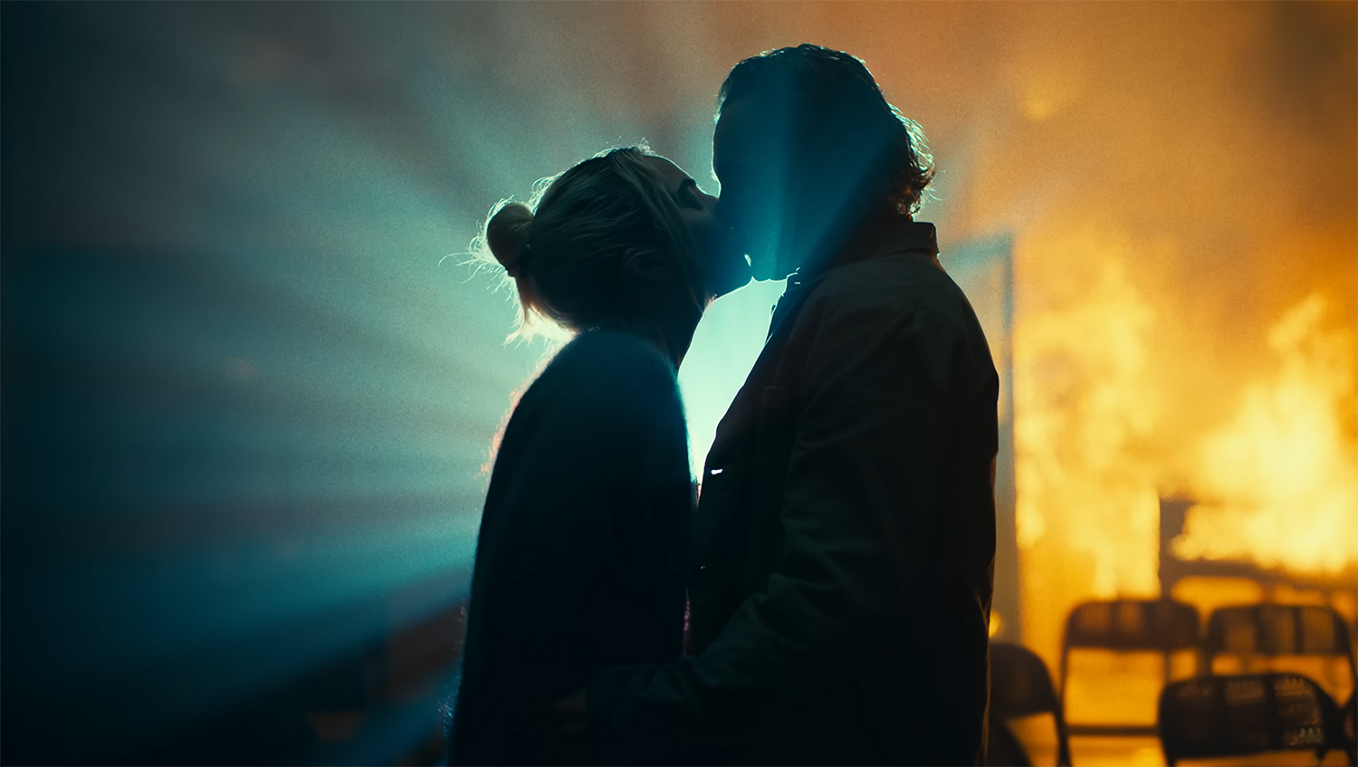 Harleen and Joker kiss while there is fire in the background.