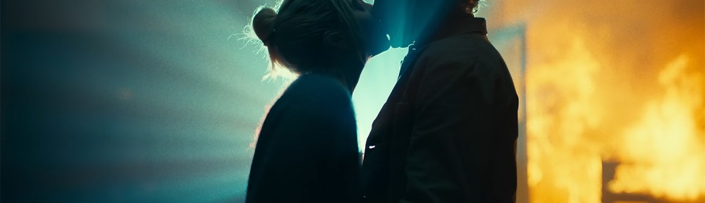 Harleen and Joker kiss while there is fire in the background.