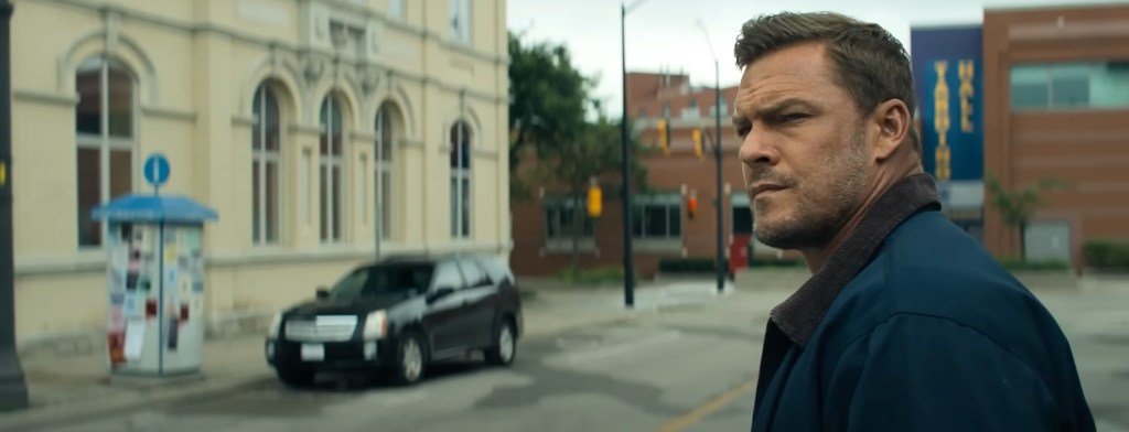 Reacher standing by a road. 