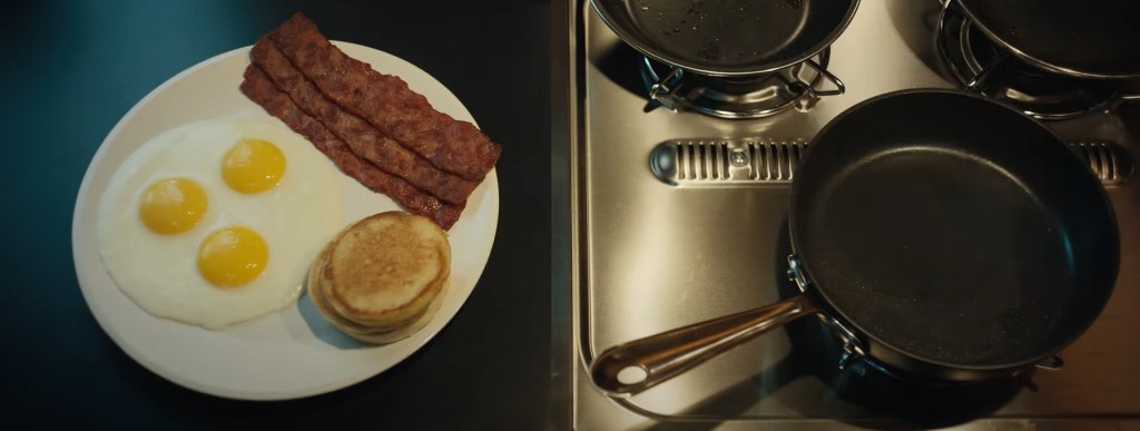 A precise breakfast of three eggs, bacon, and pancakes. 