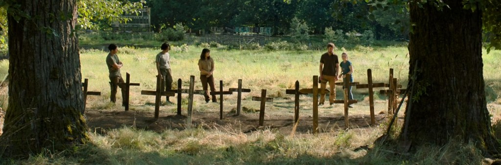 A group standing around some newly dug graves. 