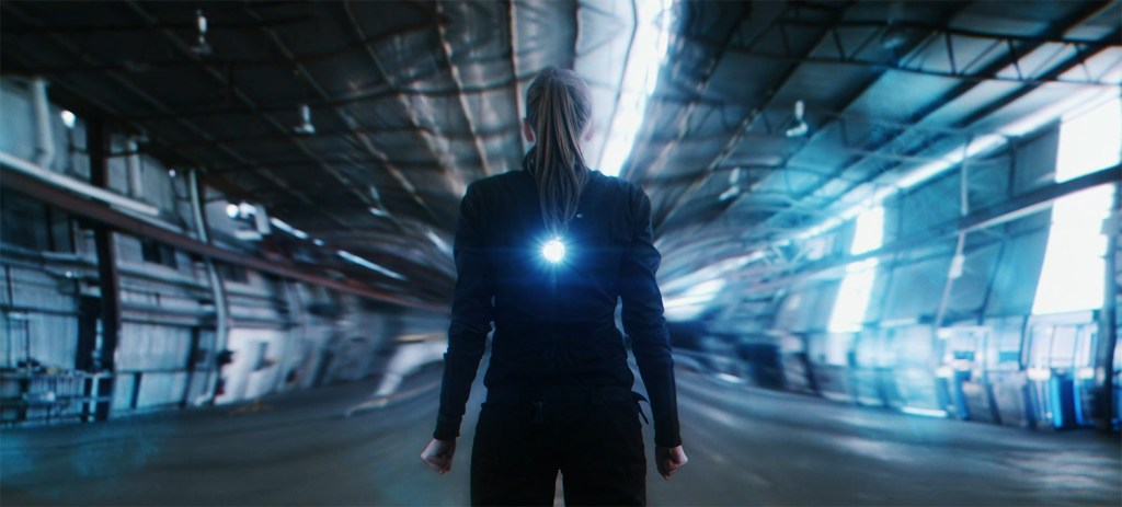 A woman stands as light and time bends around her. 