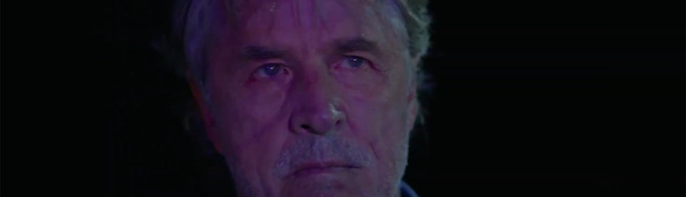 Don Johnson standing with a dour look on his illuminated face.