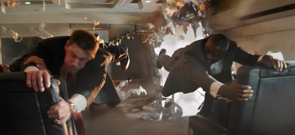 John Cena and Idris Elba hold onto seats to stop being blown out of the plane. 