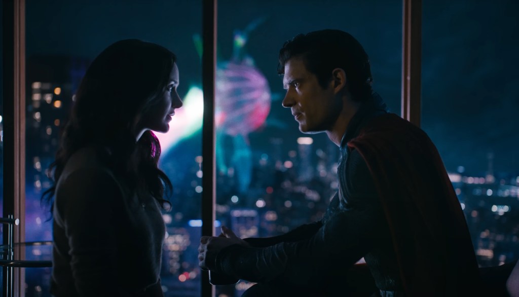 Superman and Lois look into each other's eyes while a battle happens in the background. 
