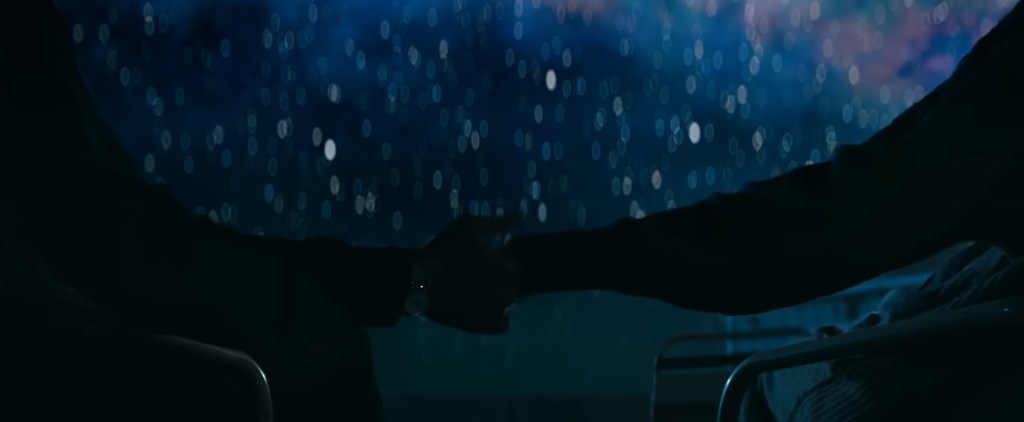 Two people hold hands as the stars shine in the background. 