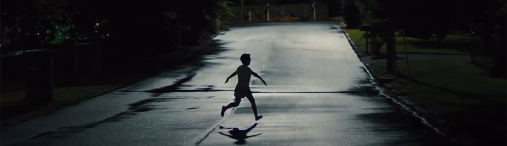 A child running in the street at night.