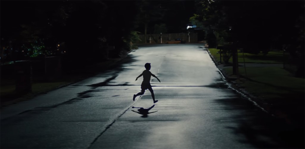 A child running in the street at night. 