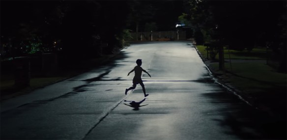 A child running in the street at night.