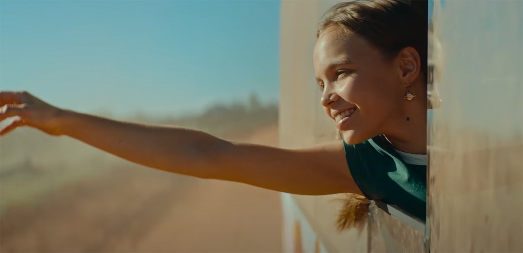 Lily Whiteley holding out of a Bus.