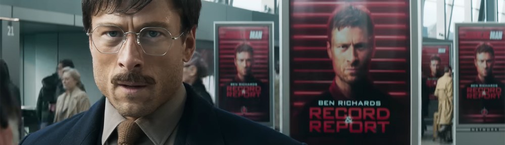 Glen Powell standing in front of posters of Glen Powell.