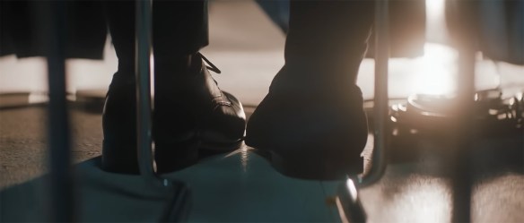 Two shoes touch under a table where no one can see. 