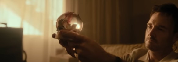 Will Forte looks at a snow globe covered in blood. 