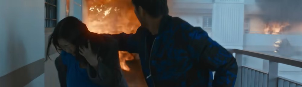 Explosions lash out from the building behind them.