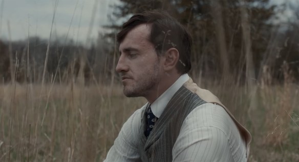 Paul Mescal sitting in a field. 