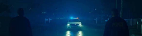A cop cruiser approaches at night. 