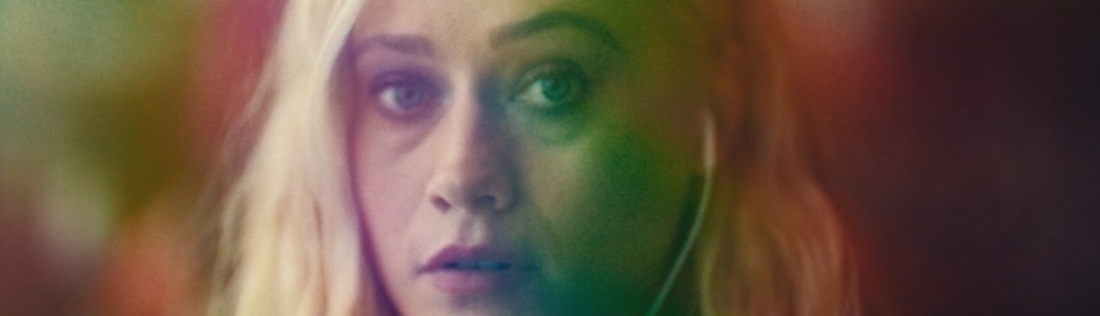 Olivia Taylor Dudley in a multi-coloured light almost like a kaleidoscope without the distortion.