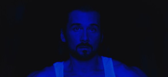 Lou Taylor Pucci illuminated by blue light. 