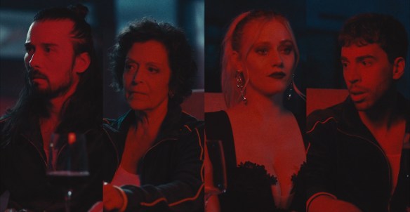 The four main cast illuminated in red light. 