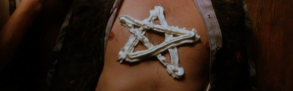 A pentagram drawn on a man's chest in whipped cream from a can. 