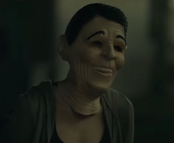 A woman in a Regan presidential rubber mask.