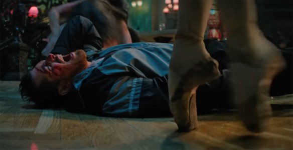 A man screams on the floor as a ballerina walks by on point. 