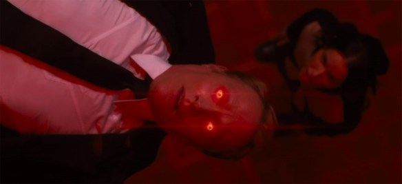 Vision floats in the air with red eyes and bathed in red light. 