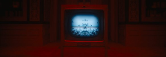 A TV bathed in red light showing a mirrored crow taking flight. 